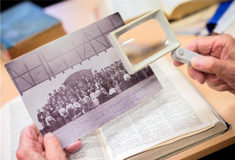 Wo die eigenen Wurzeln liegen Ein Mann sucht in der Bibliothek des Niedersächsischen Landesvereins für Familienkunde e.V. auf einem historischen Foto nach möglichen Vorfahren.
