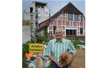 Einfahrt freihalten: Das kleine Fachwerkhaus (im Hintergrund) wird nächste Woche abgerissen. Investor Hans Kieckbusch freut sich auf den Fortgang der Arbeiten. Mit Hündin Mona sieht er sich um.