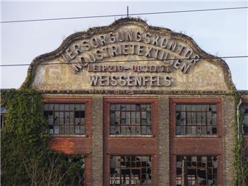Das monumentale Industriegebäude mit den drei auffälligen Giebeln erstreckt sich hinter den Gleisen des Bahnhofes von Weißenfels. Zu DDR-Zeiten war hier das Versorgungskontor Industrietextilien untergebracht.