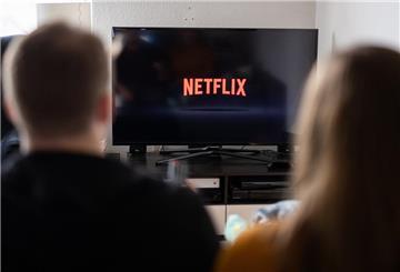 Ein Paar sitzt vor dem Fernseher, auf dem das Netflix-Logo zu sehen ist.