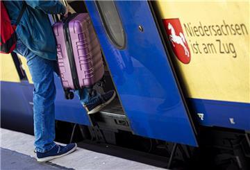 Ein Mann betritt im Hauptbahnhof Hannover mit einem Koffer eine Regionalbahn. 
