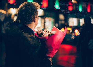 Junger Mann hält Blumenstrauß in der Hand. für sein erstes Date.