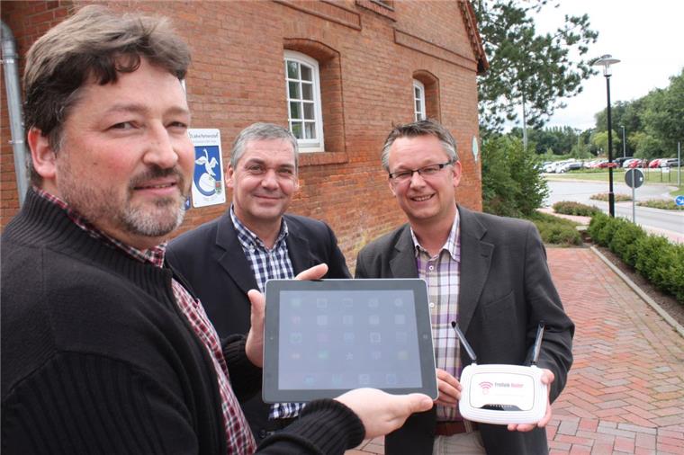 Das Rathaus beteiligt sich mit einem Verteilerknoten am Freifunk-Netz. Ralf Appel (links), Vermieter des Bürgermarktes, surft vor dem Gebäude, Bürgermeister Andreas Wittenberg (rechts) präsentiert den Router. Andreas Klimek, Geschäftsführer des Bürgermarktes, hat das Projekt initiiert.