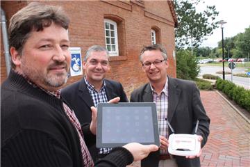 Das Rathaus beteiligt sich mit einem Verteilerknoten am Freifunk-Netz. Ralf Appel (links), Vermieter des Bürgermarktes, surft vor dem Gebäude, Bürgermeister Andreas Wittenberg (rechts) präsentiert den Router. Andreas Klimek, Geschäftsführer des Bürgermarktes, hat das Projekt initiiert.