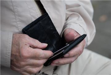 Ein Rentner hält sein Portemonnaie in der Hand.