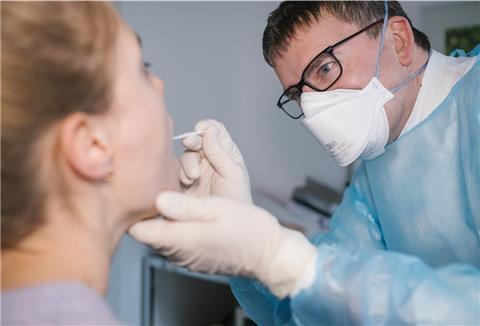 Der Facharzt für Allgemeinmedizin, Dr. Matthias Berndt nimmt bei einer Patientin einen Rachenabstrich für einen Covid-19 Schnelltest.