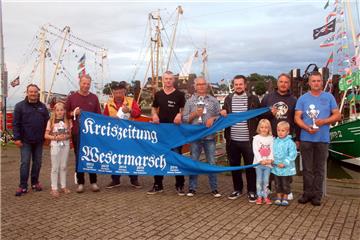 Das schnellste Schiff bei der Krabbenkutter-Regatta in Fedderwardersiel war die "Christine". Kapitän Sönke Thaden (3. von links) erhielt dafür das "Blaue Band" der Kreiszeitung Wesermarsch von Redakteur Lennart Edel (3. von rechts).