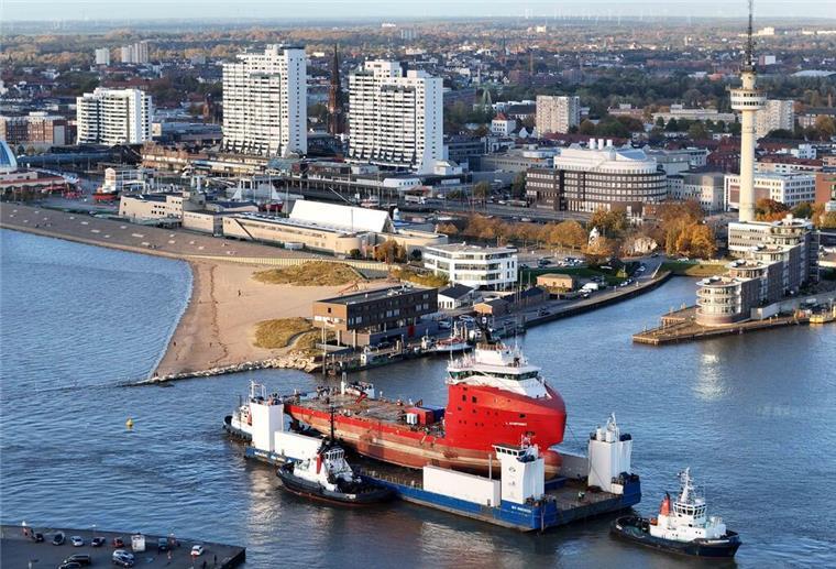 Ein Ponton, beladen mit einem Schiff, vor der Skyline Bremerhavens.