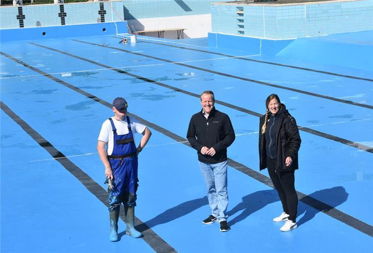 Das Foto zeigt drei Personen in einem leeren Schwimmbbecken. 