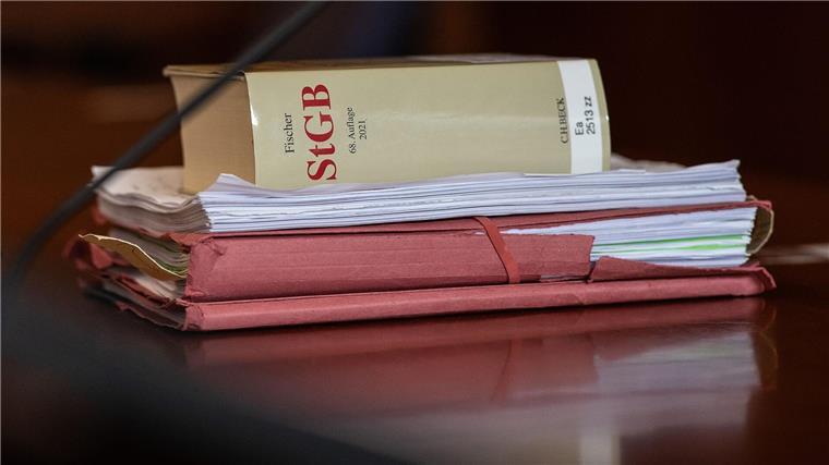 Das Strafgesetzbuch und Akten liegen in einem Gericht auf dem Tisch.