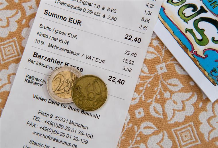 Trinkgeld als Beleidigung: Diese Besonderheiten sollten Urlauber kennen Ein Zwei-Euro-Geldstück und ein Fünfzig-Cent-Stück liegen auf einer Rechnung in einem Biergarten