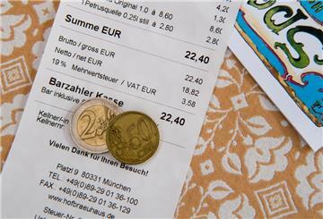 Ein Zwei-Euro-Geldstück und ein Fünfzig-Cent-Stück liegen auf einer Rechnung in einem Biergarten