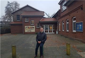 Ein Mann steht vor einer leerstehenden Schule.