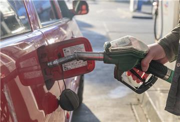 Ein Mann tankt an einer Tankstelle Benzin. An einer Autobahntankstelle ist der Preis für Sprit deutlich höher.