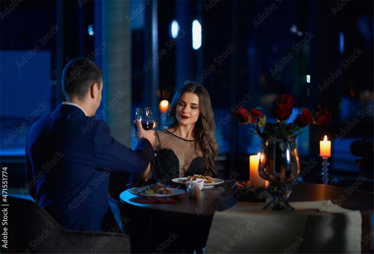 Dating-Shows im deutschen Fernsehen – Nackte Haut, Drama und große Emotionen Junges Paar sitzt in einem edlen Restaurant und stößt mit einem Glas Wein an.