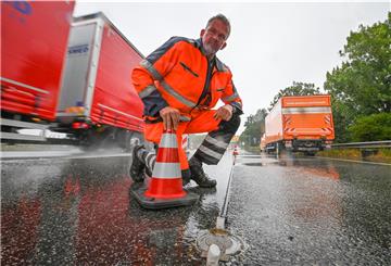 Dauerregen bremst die Arbeiten an den Markierungsleuchtknöpfen auf der Grimsbystraße aus. Christian Kluge von der Firma Siemens zeigt ein noch unfertiges Element am Boden. Foto Scheschonka
