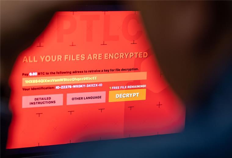 Ein Mann sitzt vor einem Laptop, der mit einem fiktiven Verschlüsselungstrojaner (Ransomware) befallen ist.