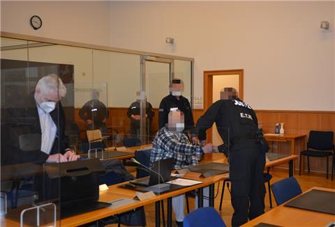 Der Angeklagte (sitzend, Mitte) sitzt aktuell in Untersuchungshaft in der JVA Bremervörde und wird zu Prozesstagen deshalb in Handschellen vorgeführt.