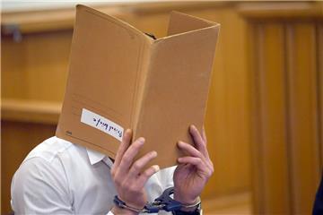 Der Angeklagte versteckt beim Prozessauftakt sein Gesicht hinter einem Aktendeckel.