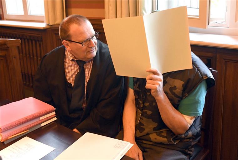Der Angeklagte versteckte sein Gesicht bei Prozessbeginn hinter einem Aktenblatt und beriet sich mit seinem Anwalt Thomas Domanski