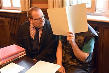 Der Angeklagte versteckte sein Gesicht bei Prozessbeginn hinter einem Aktenblatt und beriet sich mit seinem Anwalt Thomas Domanski