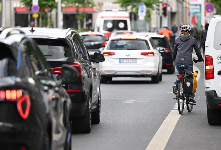Eine Fahrradfahrerin fährt an einem auf dem Radweg parkenden Auto vorbei