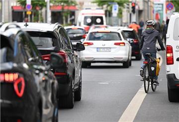 Eine Fahrradfahrerin fährt an einem auf dem Radweg parkenden Auto vorbei