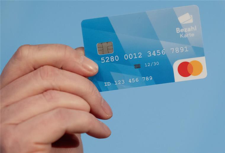 Kritik Bremerhavens wegen unterschiedlich viel Bargeld für Flüchtlinge Ein Mann hält während einer Pressekonferenz eine Bezahlkarte in der Hand.