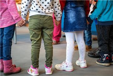 Kinder im Kindergartenalter stehen nebeneinander und halten sich an den Händen.