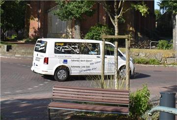 Ein Bus, ein Auto und eine Skulptur
