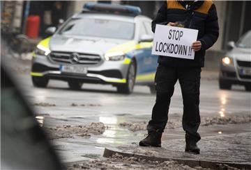Ein Mann hält ein Schild mit der Aufschrift "Stop Lockdown!!" während einer spontanen Demonstration nach einer Durchsuchung bei einem Arzt.