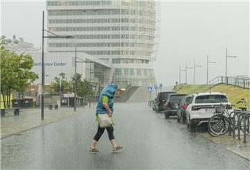 Eine Frau läuft im Regen über die Straße am Sail City Hotel in Bremerhaven.