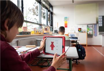 Ein Schüler arbeitet in einer Grundschule an einem Tablet. 