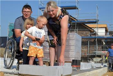 Der erste Stein steht: Marvin und Yvonne Holst verlegen gemeinsam mit ihren Kindern Fiete und Lotta den ersten Stein ihres Traumhauses.