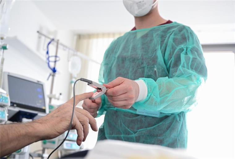  Ein Pfleger legt in einem Krankenzimmer im Klinikum Stuttgart bei einem Patienten ein Messgerät an. 