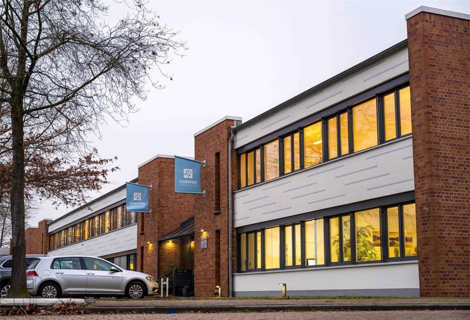 Vor einem Gebäude stehen Autos.