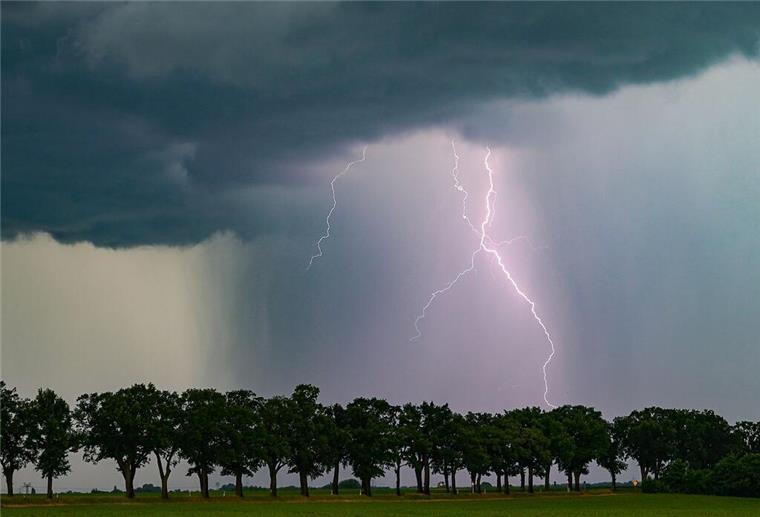 Ein Blitz leuchtet am späten Abend über der Landschaft.