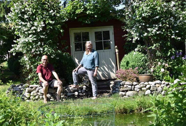 Mann und Frau vor einer Hütte in einem Garten.