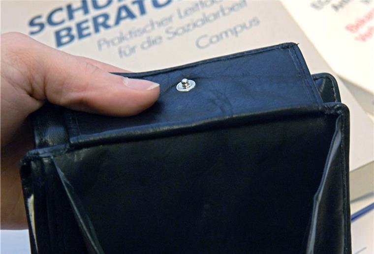 Schuldnerberater fürchten Welle 2022 Ein fast leerer Geldbeutel wird bei der Schuldnerberatung der Caritas in Hannover über Bücher zur Schuldnerberatung und der Insolvenzordnung gehalten