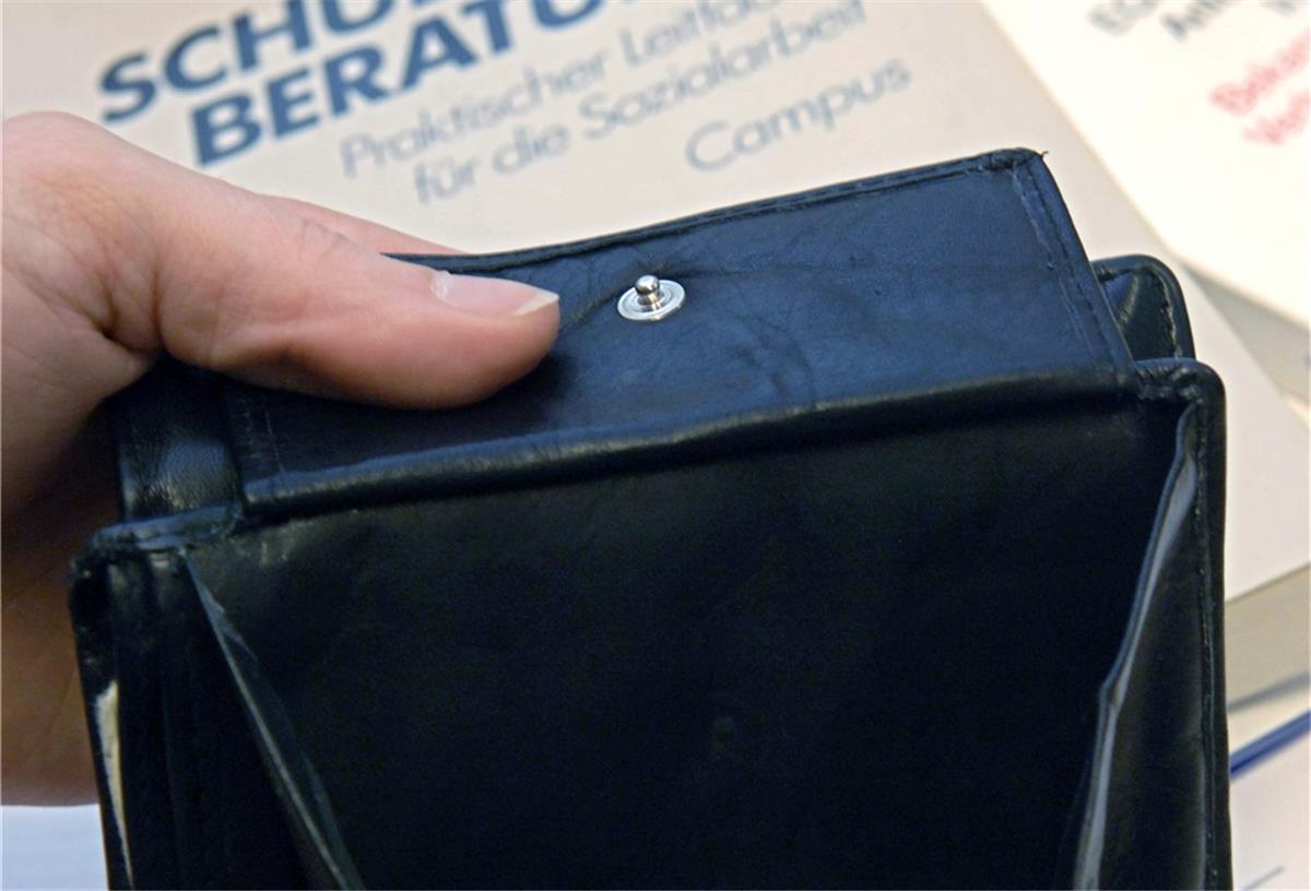 Schuldnerberater fürchten Welle 2022 Ein fast leerer Geldbeutel wird bei der Schuldnerberatung der Caritas in Hannover über Bücher zur Schuldnerberatung und der Insolvenzordnung gehalten