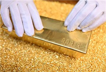 Das Bild zeigt einen Goldbarren und Feingold. Angesichts der Zölle von US-Präsident Donald Trump steigt der Goldpreis.