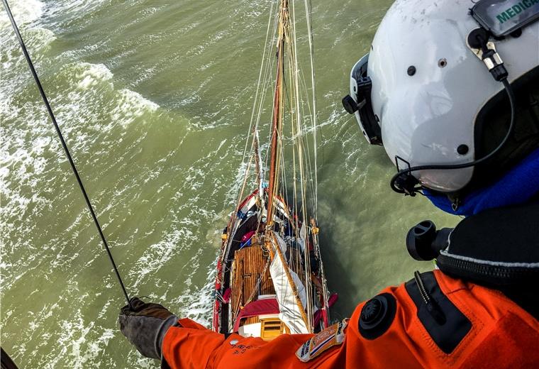 Der Helikopter „Northern Rescue 01“ steht über dem Havaristen. Ein Notfallsanitäter ließ sich per Winde auf dem Segler absetzen und holte den Segler von Bord.
