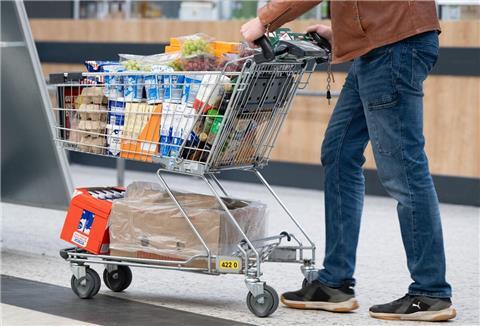 Ein Einkaufswagen im Supermarkt wird von einem Mann geschoben.