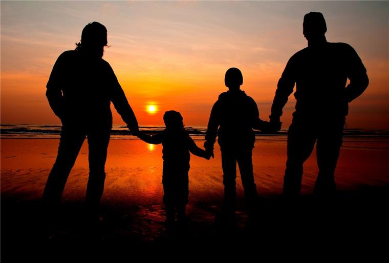 Eine Familie schaut sich einen Sonnenuntergang an.