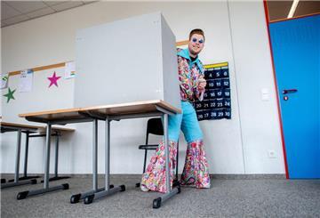 Der kostümierte Wähler Nico verlässt in einem Wahllokal nach der Stimmabgabe den Sichtschutz der Wahlkabine.