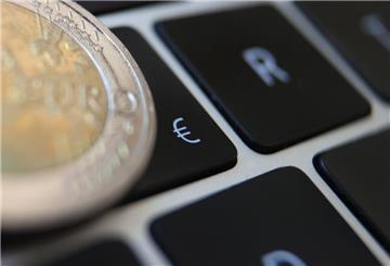 ARCHIV - 01.06.2021, Bayern, Augsburg: Eine Zwei-Euro-Münze liegt auf der Tastatur eines Laptops neben einem Eurozeichen. (zu dpa: «Für viele (noch) keine Option: Ein digitaler Euro») Foto: Karl-Josef Hildenbrand/dpa +++ dpa-Bildfunk +++