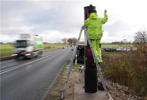 Ein Mann baut einen Blitzer an der L119 bei Neuenwalde auf.