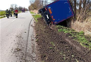 Ein umgekippter Lkw liegt am Straßenrand.
