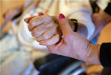Eine Pflegekraft hält die Hand einer Pflegebedürftigen. 