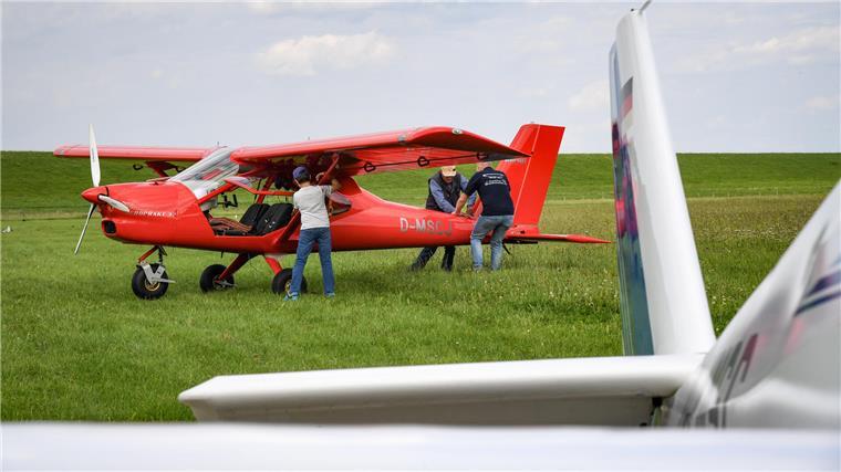 Fliegen beim MSC Bremerhaven: Gebühren, Kosten und Pflichten Ein rotes Flugzeug und drei Menschen auf einem Feld.